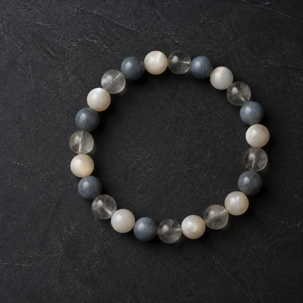 A refined bracelet made with uniform eight millimeter smoky grey, blue-grey and warm ivory stone beads